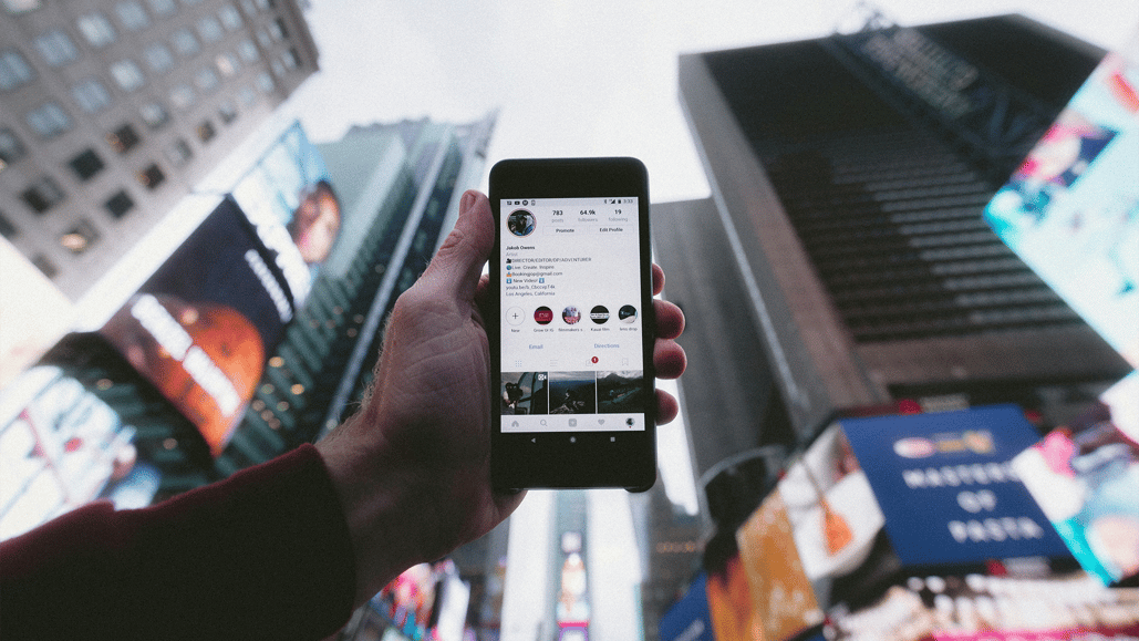 Person holding phone against a cityscape, listening to copyrighted music on Instagram