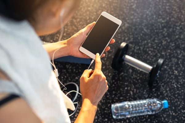 Woman listening to podcast on phone at the gym