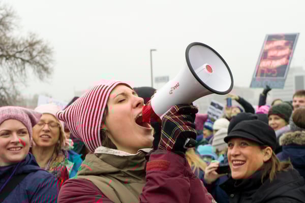 Woman-speaking-into-a-microphone-at-a-protest-march