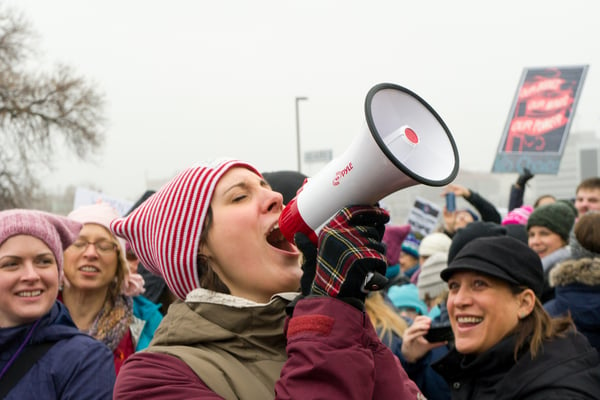 Woman-speaking-into-a-microphone-at-a-protest-march