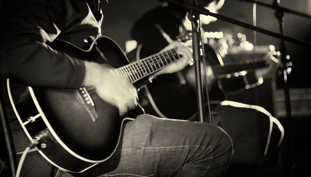 black and white photo of two people playing acoustic guitar