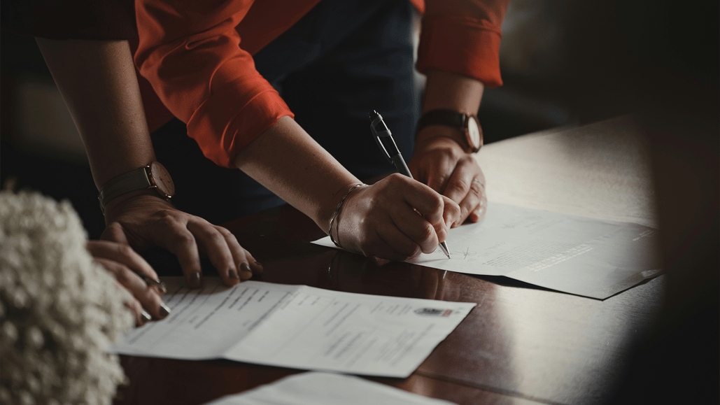 A person in an orange shirt signs a commercial music license contract for master use rights of a song