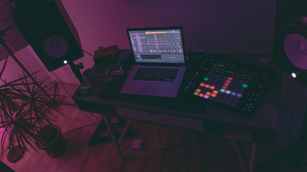 Laptop on a desk with pink and purple lighting - single-use licensing with Soundstripe