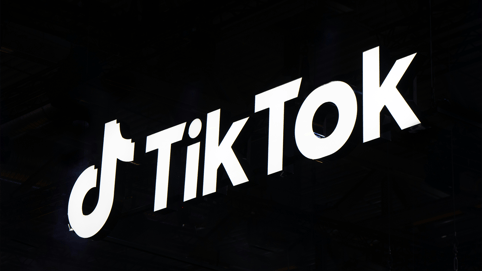 A white TikTok logo scrawls against a black background, as creators ask, “Should I make my TikTok a business account?”