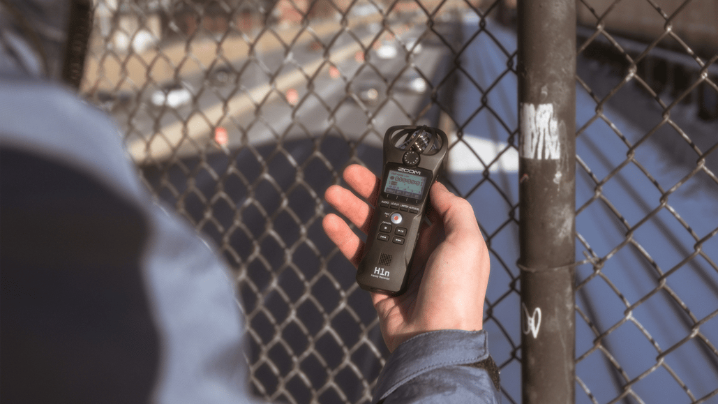 A person holds a portable digital audio recorder, after learning field recording tips to capture the best room ambience sound effects