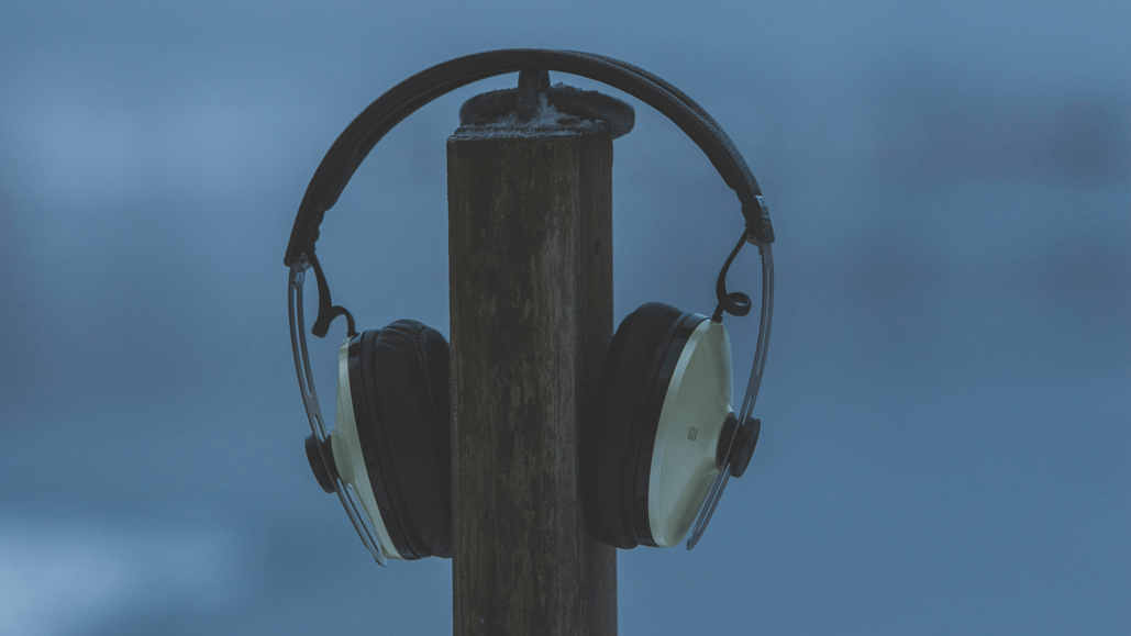 Black and silver wireless headphones sit on a stand ready to be used for listening to 3D immersive audio
