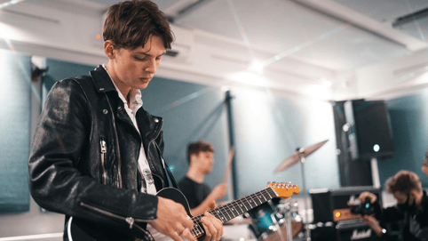 Young man playing a guitar, recording royalty free music and sound effects