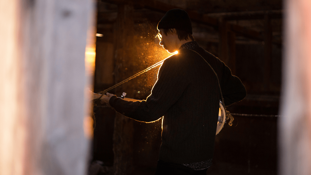 Backlit image of person playing a guitar, creating high quality royalty free music.
